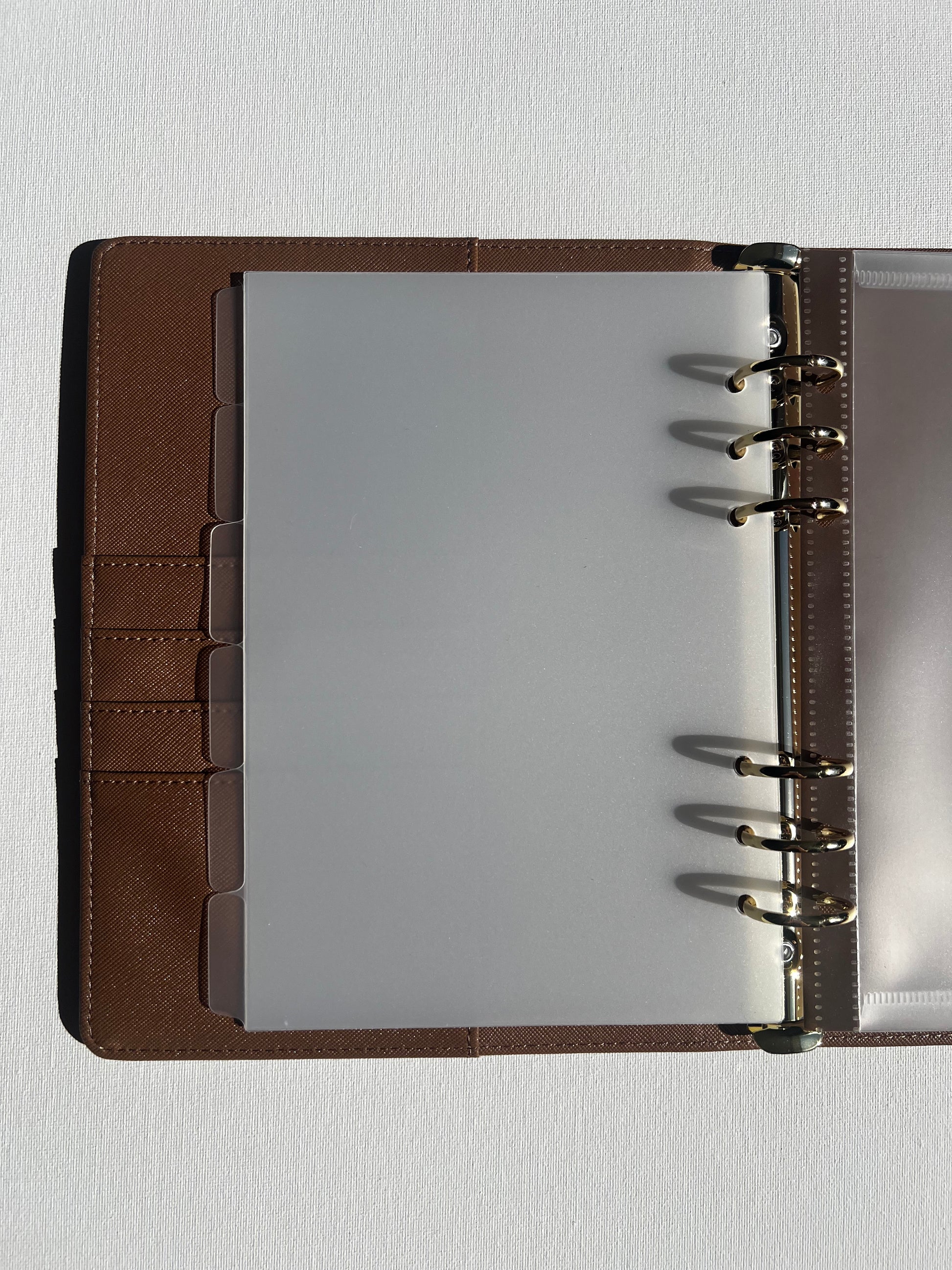 Brown leather-bound notebook with a clear plastic A5 dividers on a white background