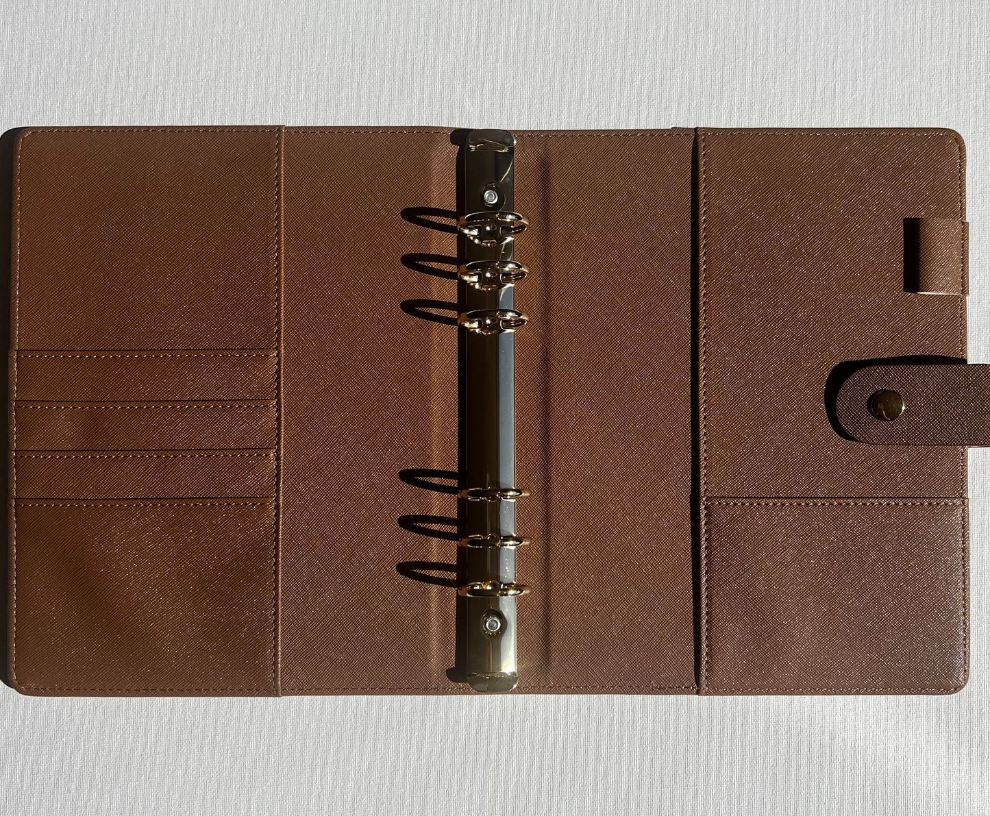 Brown leather planner with a metal ring binding on a light gray background