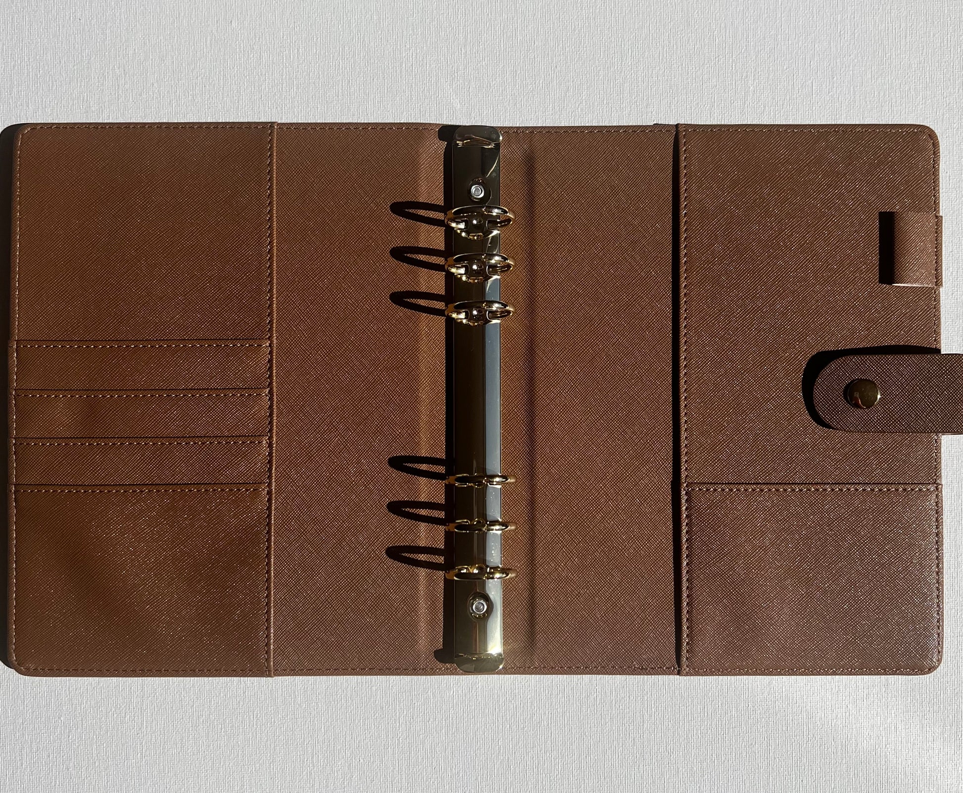 Brown leather planner with a metal ring binding on a light gray background